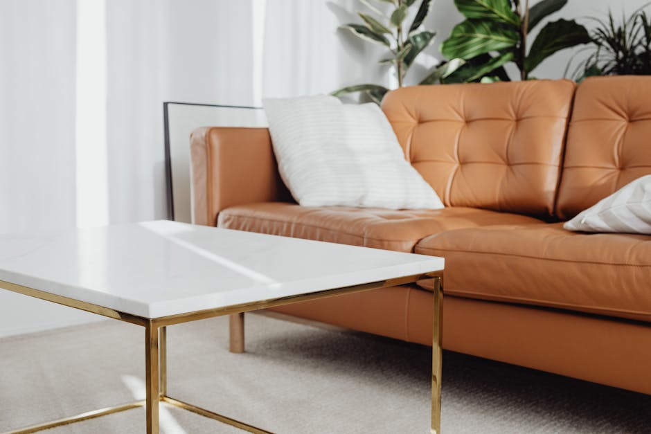 A stylish interior featuring a leather sofa, marble table, and indoor plants under natural light.
