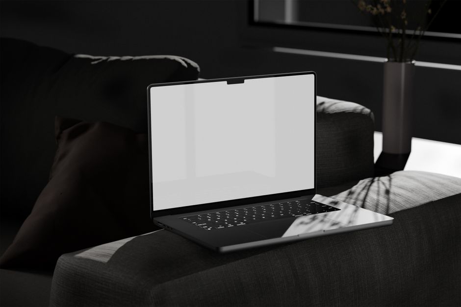 A sleek laptop with a blank screen placed on a comfortable sofa in a modern living room.