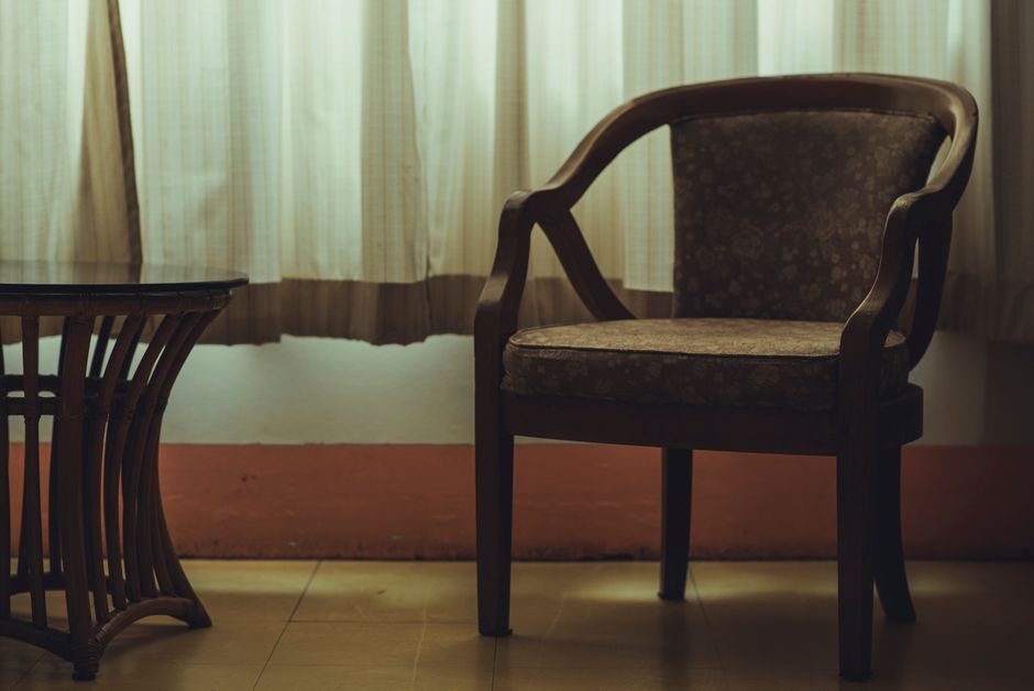 A stylish wooden armchair beside a table in a warmly lit minimalist room.