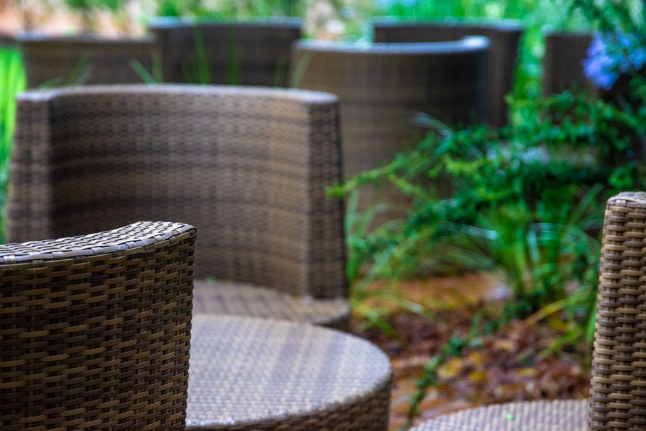 Close-up of wicker chairs in a tranquil garden setting, perfect for relaxation.