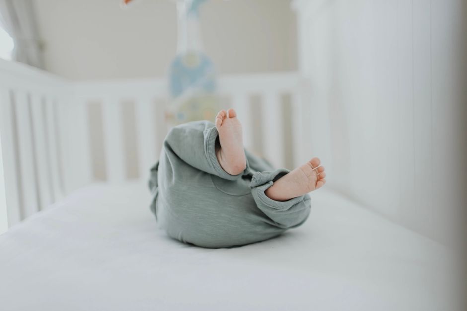 Cute baby feet in pajamas on a soft white crib. Perfect for children's room decor.