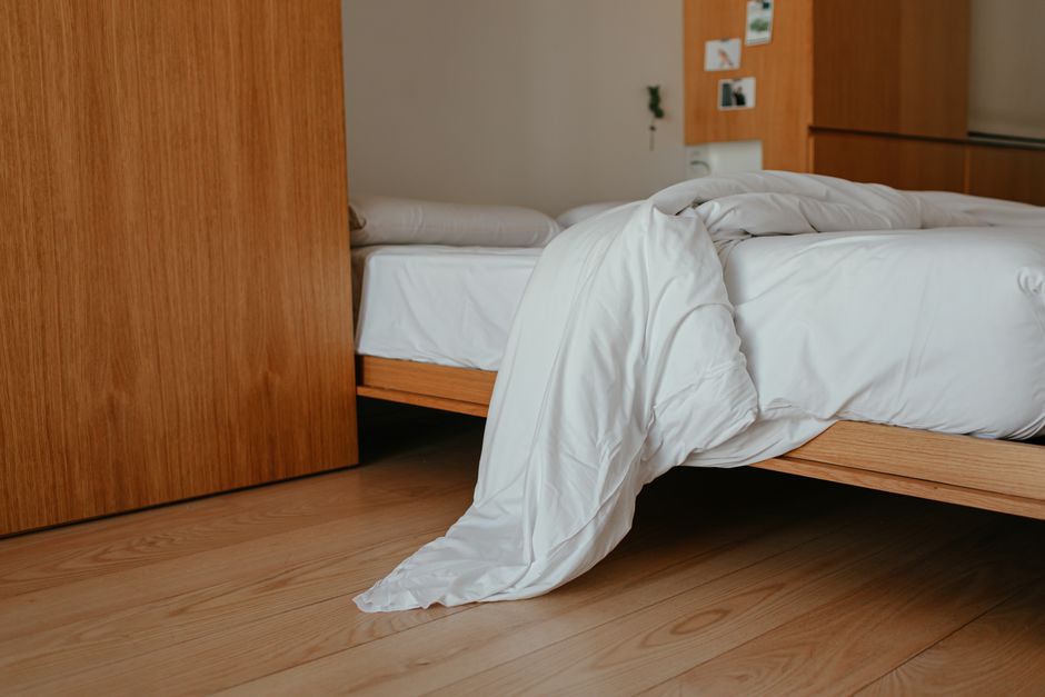 A cozy bedroom featuring a wooden bed frame with a white blanket, creating a warm and inviting atmosphere.