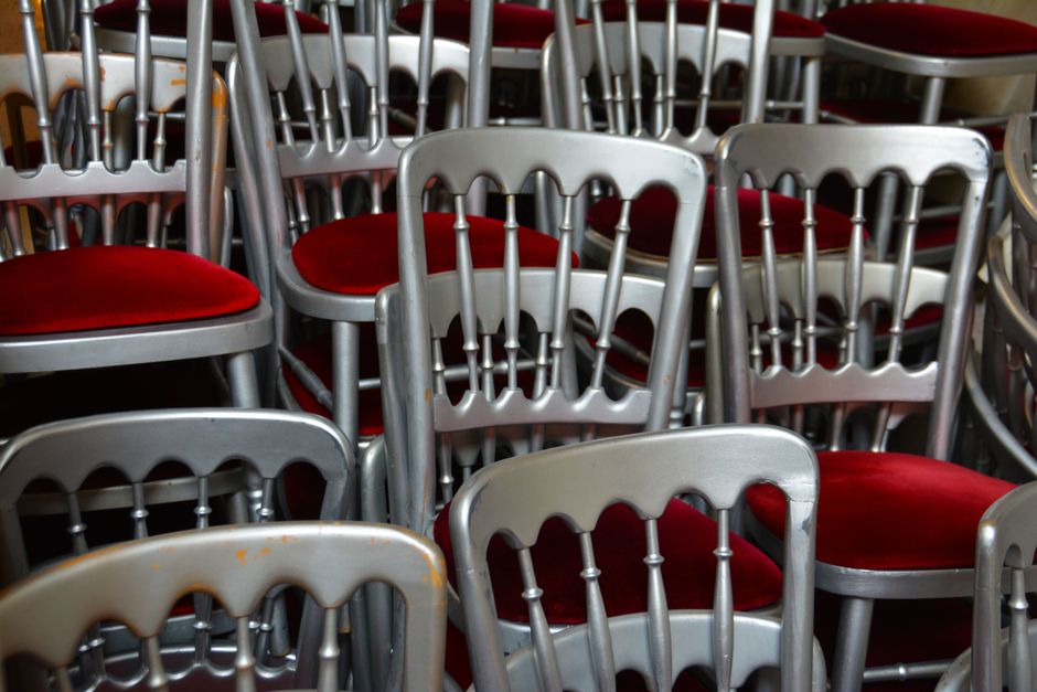 A stack of elegant silver chairs with red velvet cushions, perfect for events.