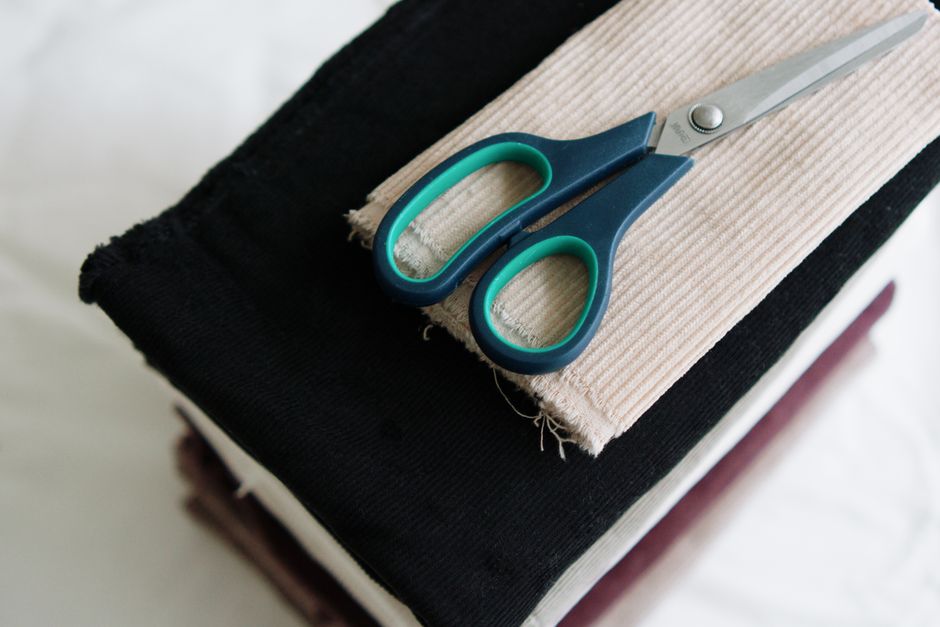 A stack of fabric with scissors, ideal for sewing projects and textile arts.