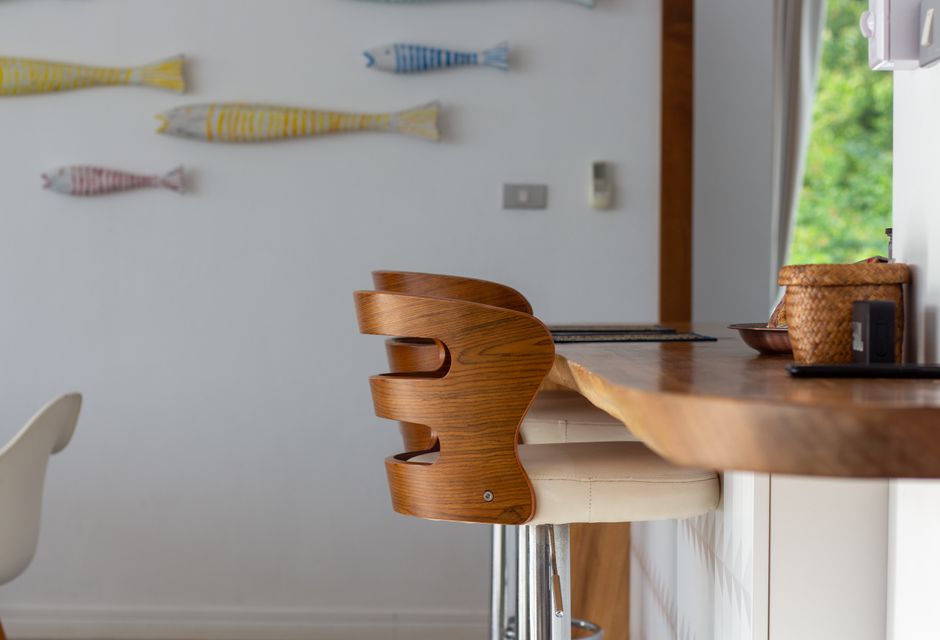 Contemporary kitchen interior featuring a wooden bar stool and decorative wall fish, offering a stylish and cozy ambiance.