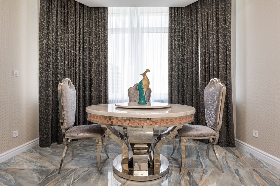 Creative design of room interior with bird statuette on table between classic chairs on marble floor in house