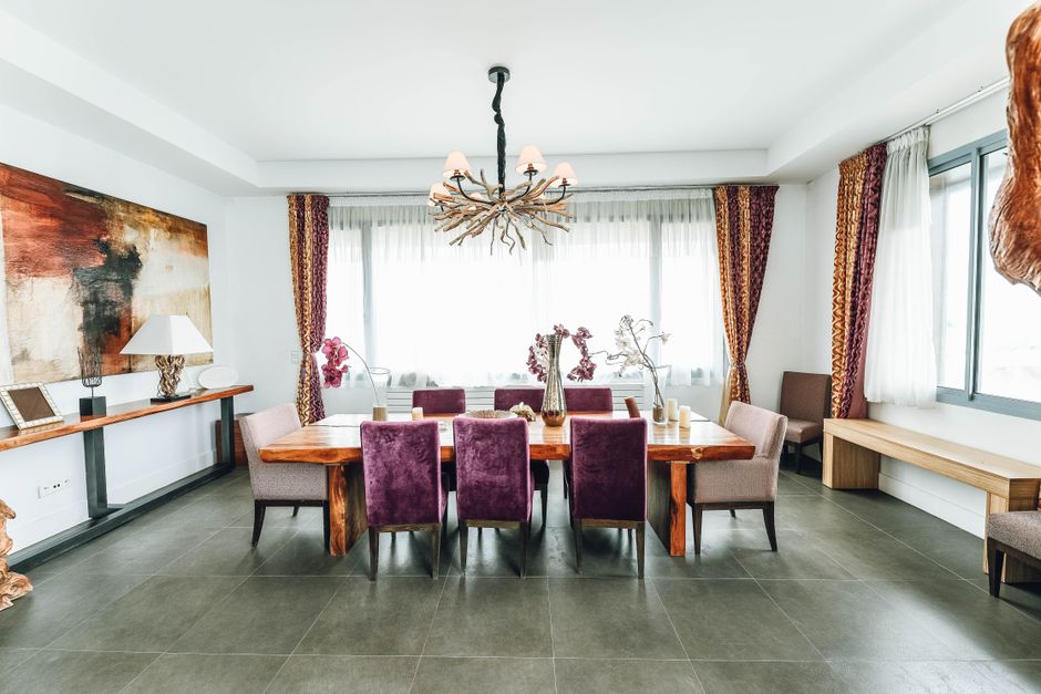 Elegant modern dining room featuring artistic decor, velvet chairs, and a unique chandelier.
