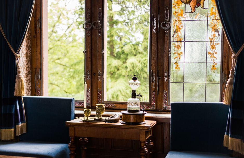 Elegant vintage interior with bright stained glass windows and classical decor table setting.