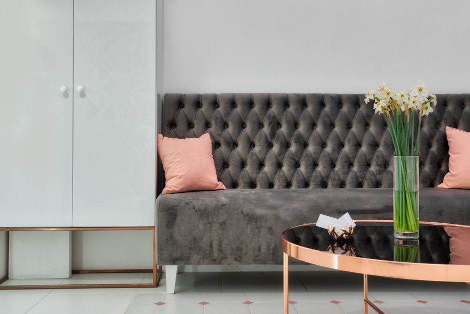 Interior design of modern lobby of clinic with sofa and stylish table decorated with bunch of daffodils in vase