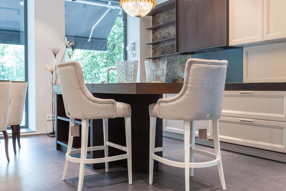 Interior of modern kitchen with table with white comfortable chairs near wooden cabinets and glass wall