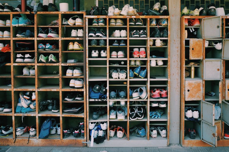 Rusted shelves filled with various shoes in a public storage area in Tokyo, Japan.