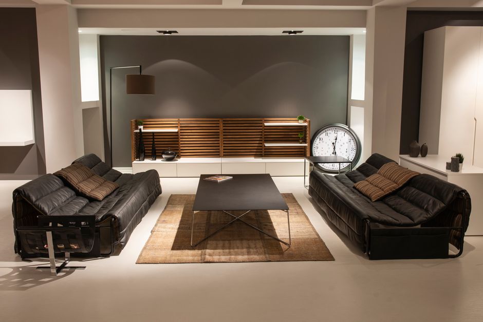Sleek modern living room with black leather sofas and elegant decor.