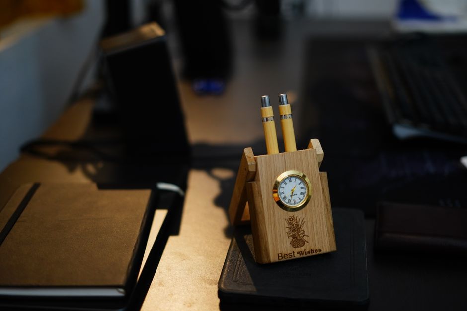 Stylish wooden desk organizer with built-in clock and pens on a modern office desk.