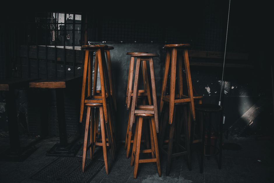 Timber bar stools and tables in aged shabby building of cafe with window with metal lattice