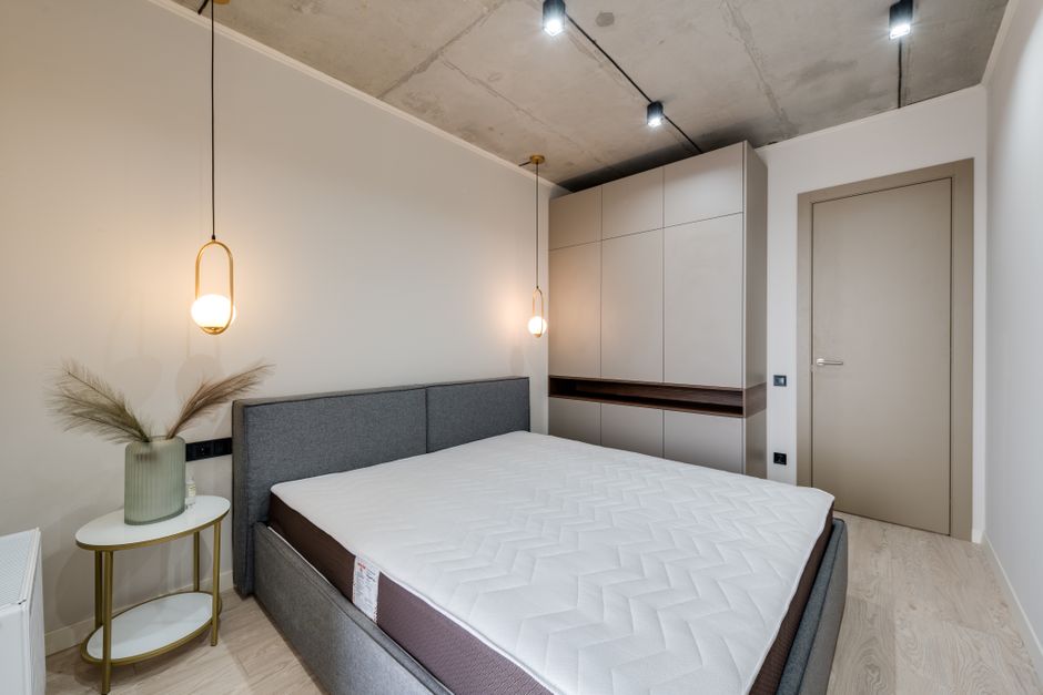 A minimalist bedroom featuring a gray bed, warm lighting, and sleek storage solutions.