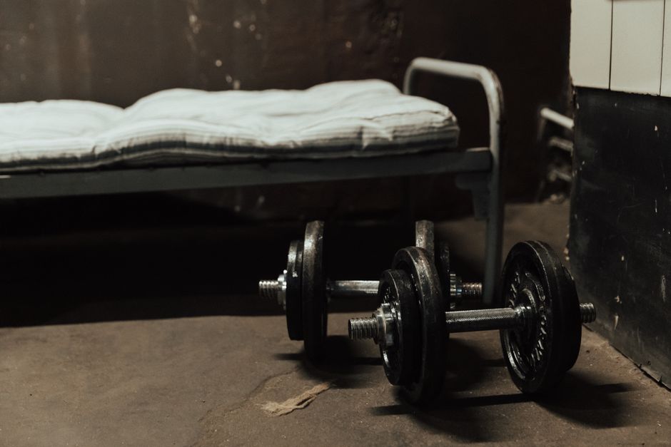 A rustic gym scene featuring dumbbells next to a bed, highlighting home workout possibilities.