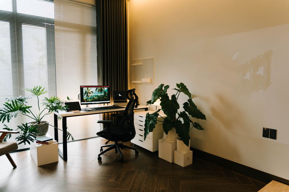 A stylish home office with contemporary furniture, lush plants, and ample natural light.