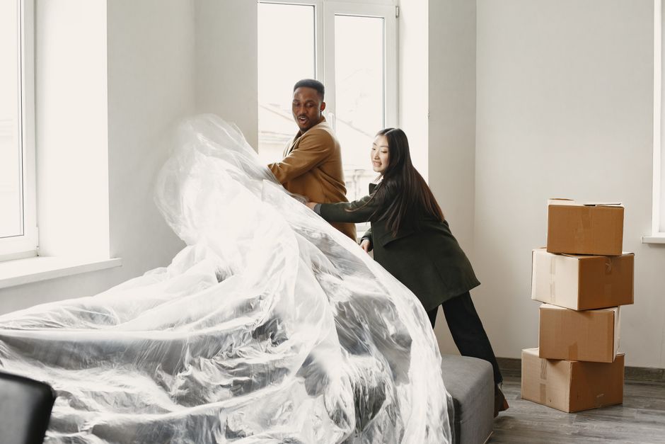 A young interracial couple joyfully unpacks furniture in their new modern apartment.