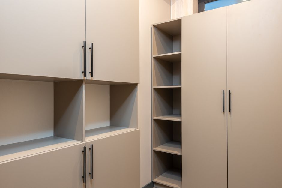 Big beige wooden wardrobe and cabinet with empty shelves placed in room in modern apartment