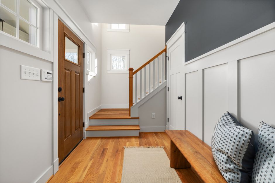 Bright and inviting entryway with wooden flooring, a bench, and natural light.