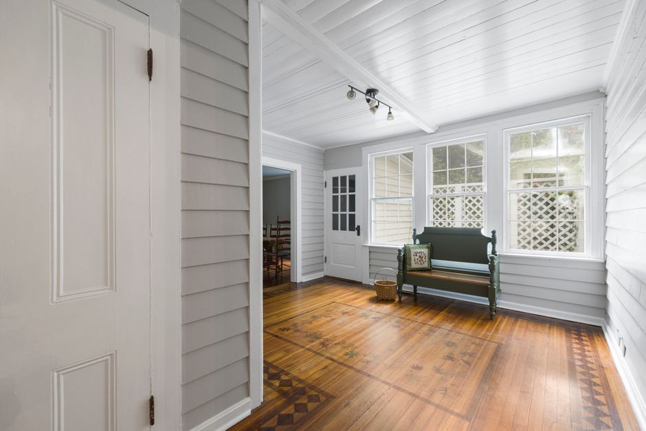 Bright interior of a sunlit porch with a classic wooden bench and elegant flooring.