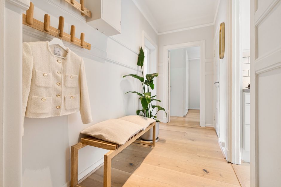 Bright minimalist hallway featuring wooden furniture and a stylish coat rack.