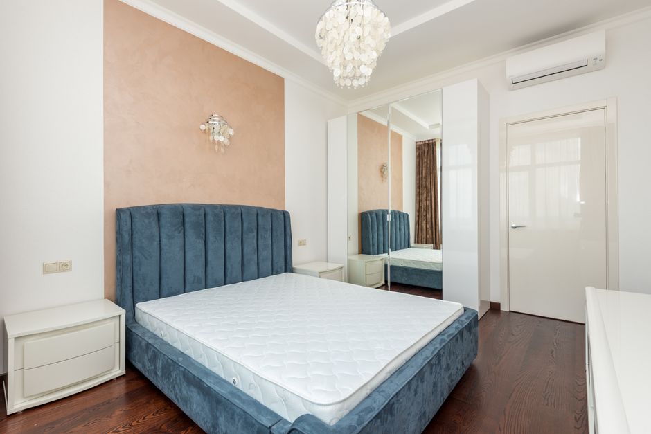 Elegant bedroom featuring a plush blue velvet bed and chic pendant light.