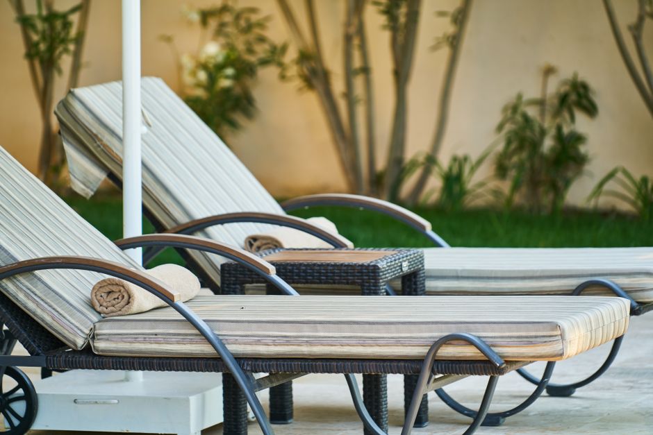 Elegant wooden sun loungers lined up poolside at a tropical resort, perfect for relaxation.
