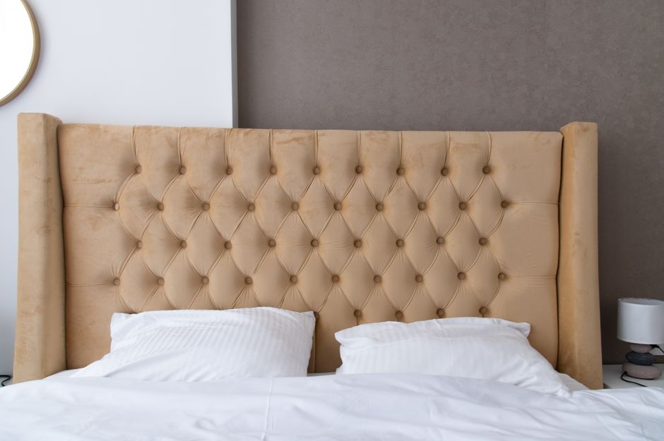 Luxurious tufted bed headboard in a stylish, modern bedroom setting with neutral tones.