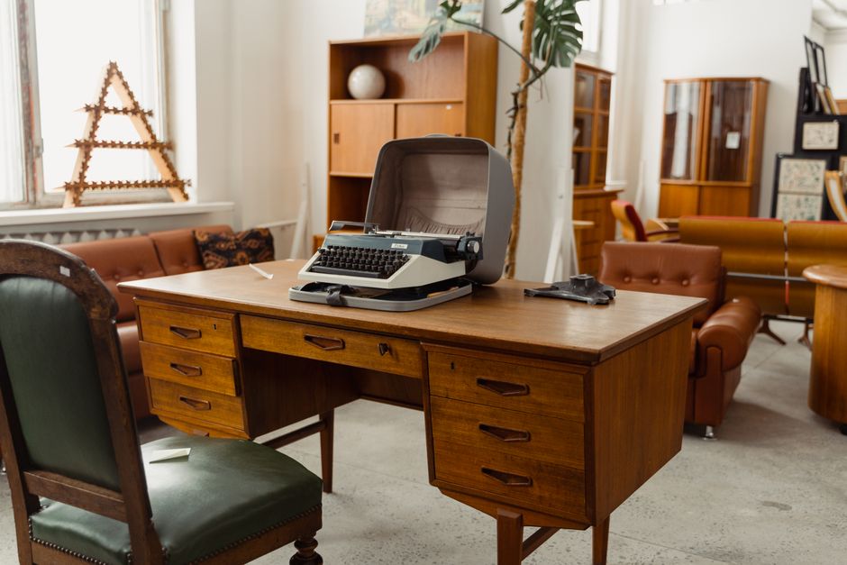 Retro office interior with a classic typewriter on a wooden desk surrounded by vintage furniture.