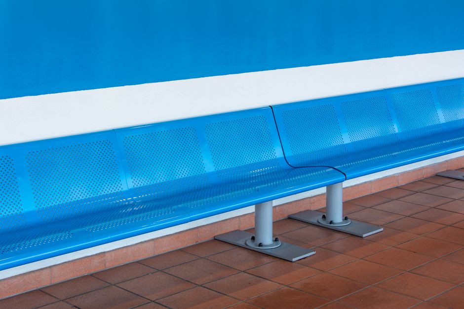 Sleek metallic blue bench in a bright, empty waiting room, highlighting minimalist design.