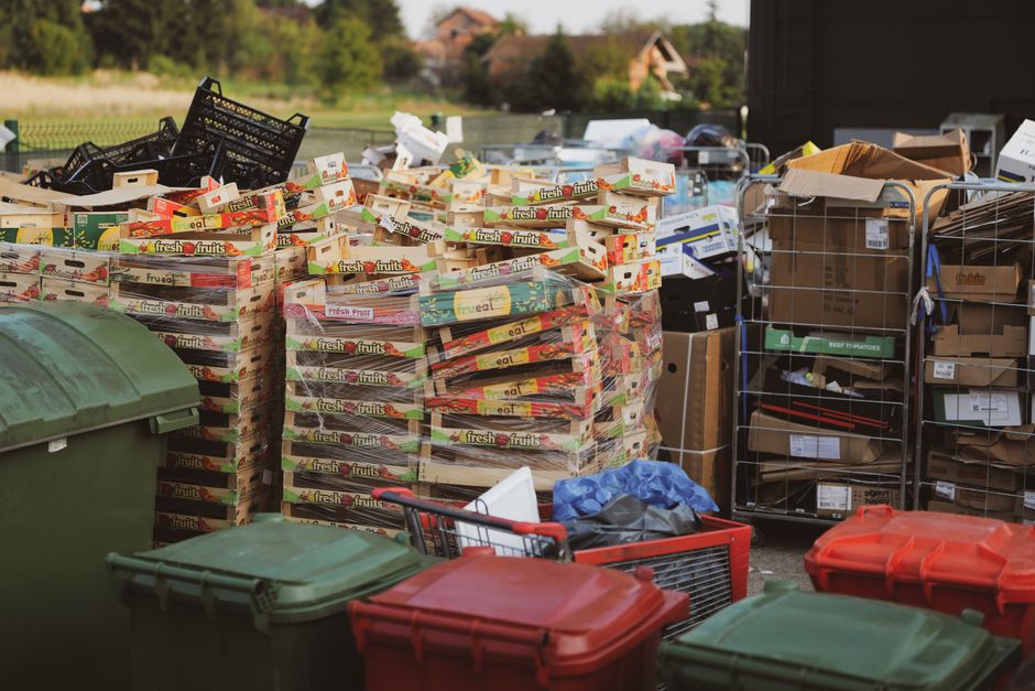 Stacks of carton boxes and bins in an outdoor storage area, exemplifying waste management.