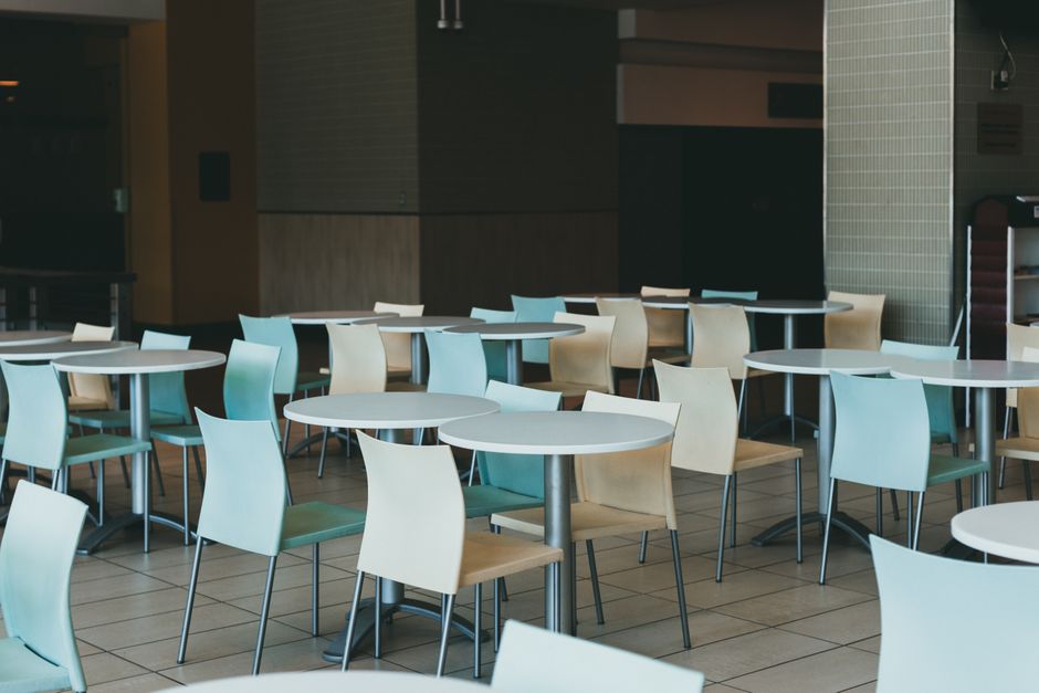 A contemporary dining area indoors with empty chairs and tables, ideal for cafes or restaurants.