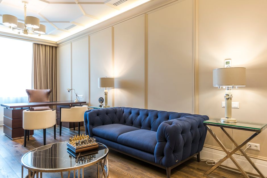 A stylish interior with modern furniture, featuring a chic blue sofa and elegant desk setup.