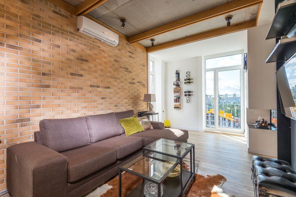 Bright living room with contemporary design, featuring a brown sofa and brick wall.