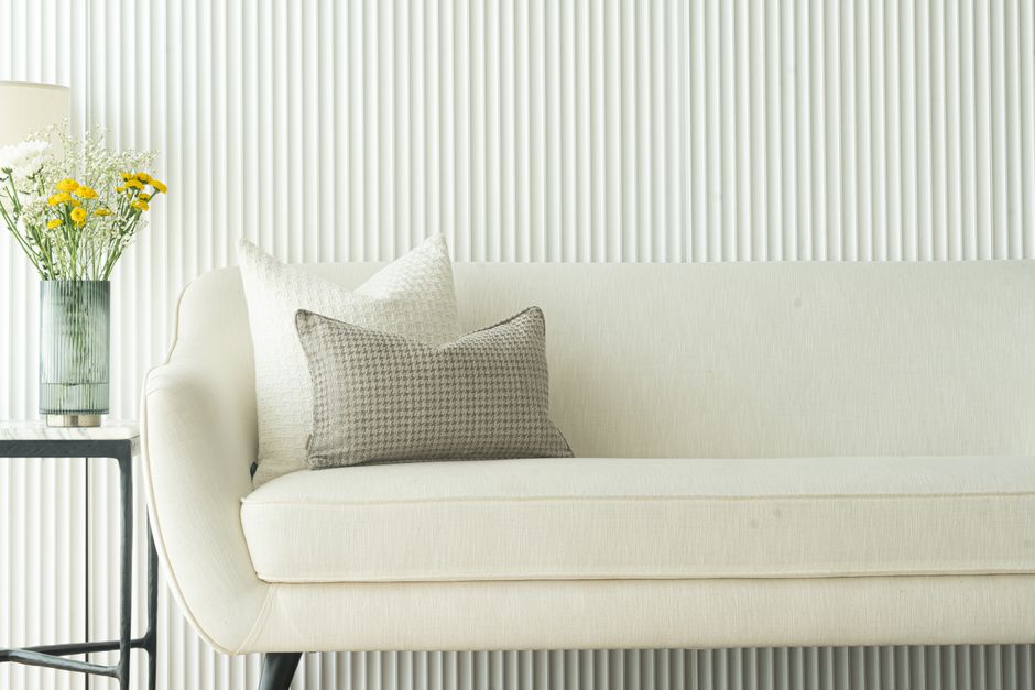 Elegant white sofa with cushions and vase of flowers, showcasing minimalist interior design in Dubai.